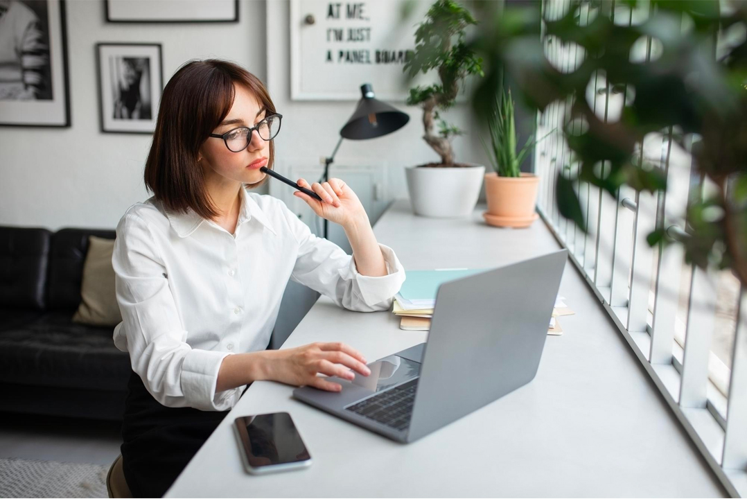 Ragazza che pensa davanti ad un laptop